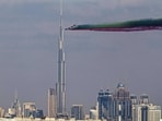 The Al-Fursan National Aerobatic team performs a commemorative flypast over the Dubai coastline and the Burj Khalifa