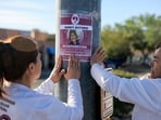 People hold a missing persons poster of Nancy Guthrie.