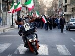 Two men on a motorcycle decorated with a picture of the late Iranian Supreme Leader Ayatollah Ali Khamenei ride ahead a group of government supporters near Khamenei's residency in Tehran, Iran, Sunday, March 1, 2026, in the aftermath of his confirmed death in U.S. and Israeli strikes.