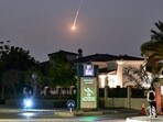 A cyclist watches as a projectile falls over Dubai amid US, Israel actions against Iran.