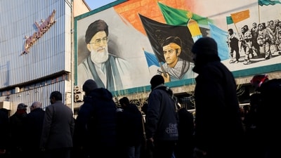 People walk near a mural featuring an image of Iran's Supreme Leader Ayatollah Ali Khamenei as people gather after Khamenei was killed in Israeli and U.S.&nbsp; (via REUTERS)
