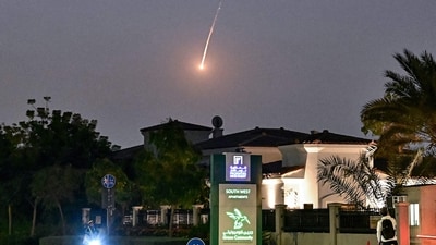 A cyclist watches as a projectile falls over Dubai amid US, Israel actions against Iran. (AFP)