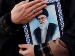 A woman holds a photo frame of Iran's Supreme Leader Ayatollah Ali Khamenei after he was killed in Israeli and US strikes on Saturday in Tehran. (via Reuters)