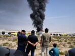 Dubai-Abu Dhabi news highlights: Residents watch as the flames and a black plume of smoke rises from a warehouse at the industrial area of Sharjah City in the United Arab Emirates.