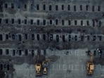 Iran bombing: White chalk rectangles mark each burial plot, while mourners gather nearby in what appears to be a somber funeral preparation.
