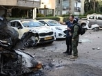 Israeli security forces stand next to the wreckage of cars as they inspect a site struck by a projectile in Ramat Gan near Tel Aviv. Israeli security forces stand next to the wreckage of cars as they inspect a site struck by a projectile in Ramat Gan near Tel Aviv.