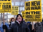 A person holds placards and chants slogans as they rally during a protest against US military action in Iran