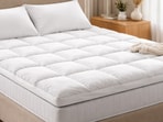 A plush mattress topper neatly layered on a double bed, adding softness and support for restful nights without replacing the mattress.