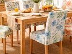 Colourful printed chair covers styled around a sunny dining table, adding fresh patterns and cheerful summer energy to everyday meals.(Ai generated)