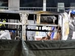 Fire investigators examine the charred shell of a postal bus that caught fire in Kerzers, Switzerland, Tuesday, March 10, 2026, after several passengers were killed and others injured when a postal bus caught fire late Tuesday afternoon in the center of Kerzers, according to the Fribourg cantonal police. 