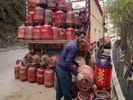 A worker off-loads LPG cylinders from a carrier truck, in Shimla, on Wednesday. (PTI)