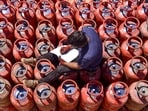 A worker sits over LPG cylinders during distribution at a gas agency, in Chikkamagaluru, Karnataka, Wednesday.