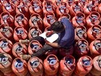 A worker sits over LPG cylinders during distribution at a gas agency, in Chikkamagaluru, Karnataka, Wednesday.