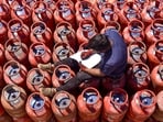 A worker sits over LPG cylinders during distribution at a gas agency, in Chikkamagaluru, Karnataka, Wednesday.
