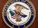 The seal of the Dept of Justice is shown on the podium. The seal of the Dept of Justice is shown on the podium.