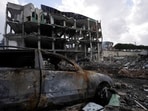 A damaged car near a damaged building in the aftermath of an Israeli strike on a healthcare center.