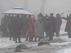 People gather during fresh snowfall, in Gulmarg, on Sunday. (PTI)