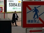 A man walks past a screen displaying Japan's Nikkei share average outside a brokerage in Tokyo, Japan.