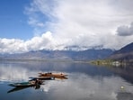 A man on a boat at Dal Lake in Srinagar on Tuesday. Weather improved across Jammu and Kashmir on Tuesday amid predictions by the meteorological centre of more rains and snowfall for the next few days which may coincide with the upcoming Eid. (ANI)
