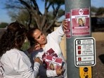 People put up posters as the search for Nancy Guthrie continues.