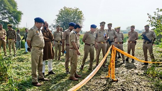 Police investigate at the site where the body of a missing 11-year-old girl was allegedly found buried in a field at the Ghatampur-Bidhnu area, Kanpur (PTI)