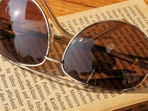 Classic aviator sunglasses resting on a sunlit table, ready to complement any outfit and suit every face shape effortlessly.