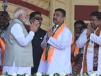PM Narendra Modi greets BJP leaders Suvendu Adhikari and Sukanta Majumdar during a poll rally at Brigade Parade Ground in Kolkata on March 14, 2026.