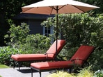 A large garden umbrella casting cool shade over a patio seating area, perfect for relaxed summer afternoons with family outdoors.