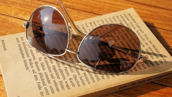 Classic aviator sunglasses resting on a sunlit table, ready to complement any outfit and suit every face shape effortlessly. (pexels.com)