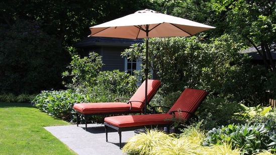 A large garden umbrella casting cool shade over a patio seating area, perfect for relaxed summer afternoons with family outdoors. (AdobeStock)