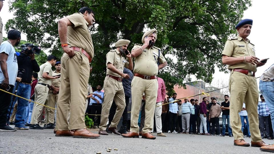 Chandigarh Police at the crime spot in the Sector 9 market parking lot on Wednesday. The area was cordoned off. Empty cartridges can be seen in the foreground. (Keshav Singh/HT) Chandigarh Police at the crime spot in the Sector 9 market parking lot on Wednesday. The area was cordoned off. Empty cartridges can be seen in the foreground. (Keshav Singh/HT)
