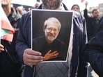 A mourner holds a picture of Iran's security chief Ali Larijani during his funeral alongside Gholamreza Soleimani, a senior officer in the Islamic Revolutionary Guard Corps who commands Basij forces, in Tehran on March 18, 2026. 