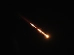 Trails of a cluster missile fired from Iran cross the sky over Tel Aviv, Israel, Wednesday.