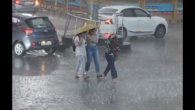 People seen caught in the sudden rain at Hazratganj crossing in Lucknow on Friday. (Deepak Gupta/HT)