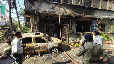 Police personnel and people gather as a rescue operation is underway after a fire broke out in a house in Indore, Madhya Pradesh, on Wednesday. (PTI) (HT_PRINT)