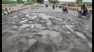 The sector road seen filled with potholes on Friday, making commuting difficult. (Parveen Kumar/HT)