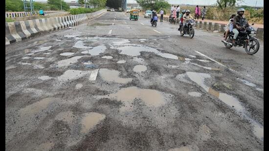 The sector road seen filled with potholes on Friday, making commuting difficult. (Parveen Kumar/HT)