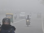 Commuters make their way amid dense fog on an early morning near Raj Ghat, in New Delhi.