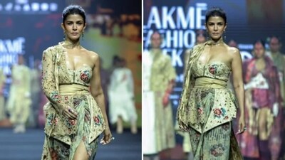Nimrat Kaur turned heads, flaunting an avant-garde look as she walked for Jajaabor at LFW 2026. The outfit consists of a heavily embroidered, asymmetrical wrap skirt with a high slit, paired with a structured, one-shoulder corset bodice. The fabric is a luxurious blend of muted beige and sage green, adorned with intricate floral motifs and a shifted leaves print. A delicate, long-line lace overlay adds a regal, flowing silhouette. Statement rings, drop earrings, and high silver heels complete the ensemble. (@fdciofficial/Instagram) Nimrat Kaur turned heads, flaunting an avant-garde look as she walked for Jajaabor at LFW 2026. The outfit consists of a heavily embroidered, asymmetrical wrap skirt with a high slit, paired with a structured, one-shoulder corset bodice. The fabric is a luxurious blend of muted beige and sage green, adorned with intricate floral motifs and a shifted leaves print. A delicate, long-line lace overlay adds a regal, flowing silhouette. Statement rings, drop earrings, and high silver heels complete the ensemble. (@fdciofficial/Instagram)