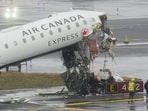 Officials investigate the site, Monday, March 23, 2026, where an Air Canada jet came to rest after colliding with a Port Authority firetruck at LaGuardia Airport