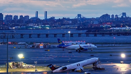 A plane takes off behind the wreckage of an Air Canada jet and Port Authority fire truck that collided at LaGuardia Airport, March 23, in New York. (AP)