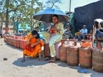Women sit on empty LPG cylinders as they wait in a queue outside a gas agency to avail the refilled ones amid ongoing supply disruptions, in Ranchi, Wednesday, March 25, 2026.