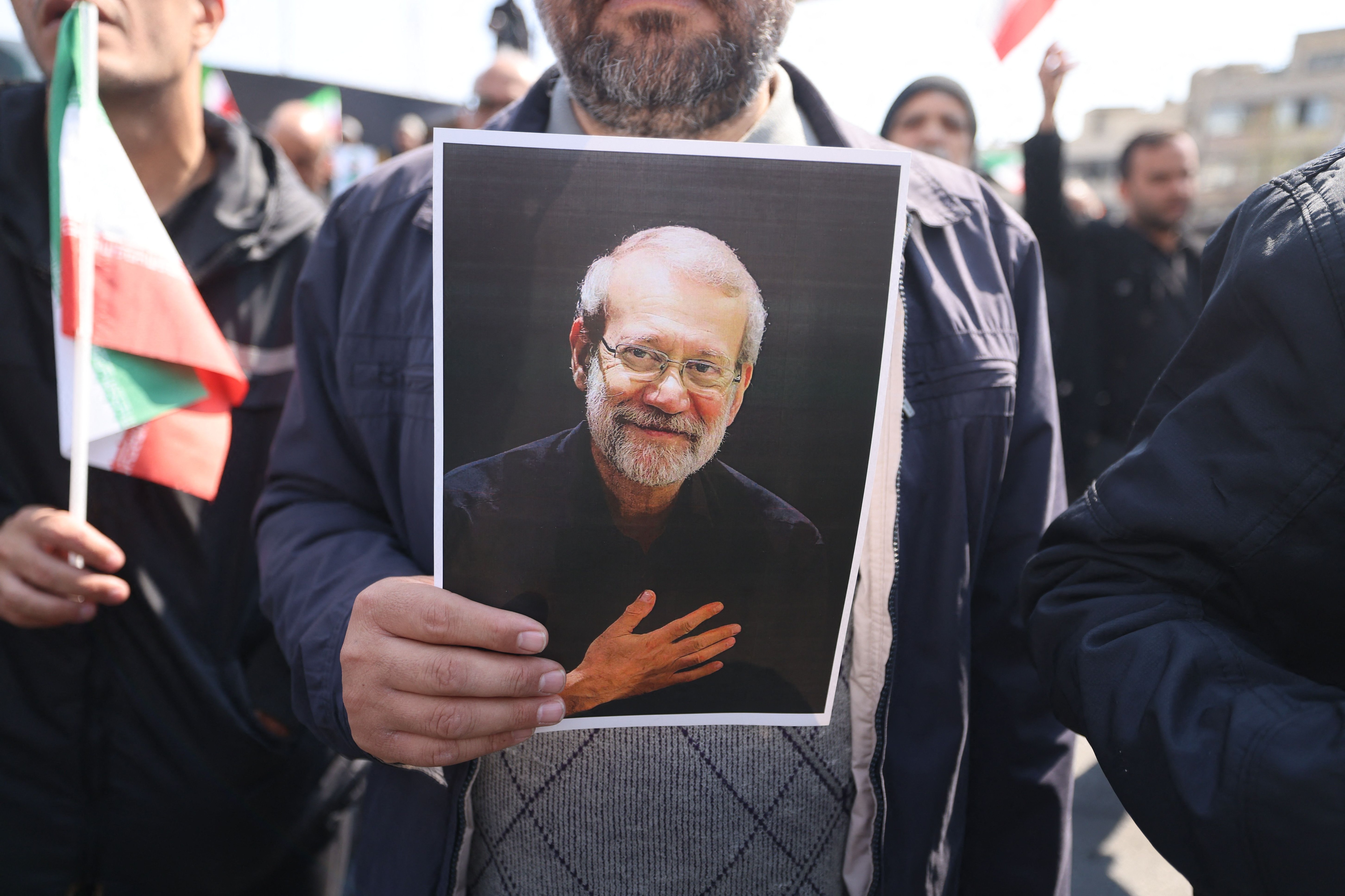 A mourner holds a picture of Ali Larijani during his funeral in Tehran on March 18, 2026. Iran's new Supreme Leader Mojtaba Khamenei declared in a written message that his killers would pay. Larijani's funeral was held alongside those of Gholamreza Soleimani, the head of the Basij paramilitary force who was also killed in a strike inside Iran by US-Israeli forces. (AFP Photo) A mourner holds a picture of Ali Larijani during his funeral in Tehran on March 18, 2026. Iran's new Supreme Leader Mojtaba Khamenei declared in a written message that his killers would pay. Larijani's funeral was held alongside those of Gholamreza Soleimani, the head of the Basij paramilitary force who was also killed in a strike inside Iran by US-Israeli forces. (AFP Photo)