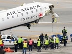 Airport firefighting and maintenance crews remove loose debris from the wreckage of an Air Canada Express jet, Wednesday, March 25, 2026.