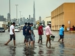 People cross a street through floodwaters after heavy rains in Dubai on March 27, 2026. (Photo by FADEL SENNA / AFP)