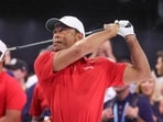 Tiger Woods hits a practice iron from a grass pad before the TGL finals golf tournament in Palm Beach Gardens