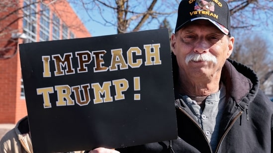 A man holds a sign reading "Impeach Trump" as he takes part in the "No Kings" national day of protest in Howell, Michigan, on March 28, 2026.&nbsp;(AFP)