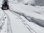 Snow clearance underway on a road following a fresh spell of snowfall in Bandipora on Sunday. (ANI)