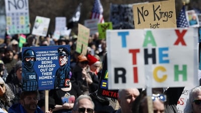 A person holds a sign with a quote from Anne Frank and featuring an ICE agent and a Nazi Germany-era soldier as they rally at Grant Park during the "No Kings" national day of protest in Chicago on March 28, 2026. (Photo by KAMIL KRZACZYNSKI / AFP) (AFP) A person holds a sign with a quote from Anne Frank and featuring an ICE agent and a Nazi Germany-era soldier as they rally at Grant Park during the "No Kings" national day of protest in Chicago on March 28, 2026. (Photo by KAMIL KRZACZYNSKI / AFP) (AFP)