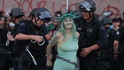 LAPD officers arrest a protester dressed as Lady Liberty in chains following clashes near the Metropolitan Detention Center during the "No Kings" national day of protest in Los Angeles on March 28, 2026. (Photo by Etienne LAURENT / AFP) (AFP) LAPD officers arrest a protester dressed as Lady Liberty in chains following clashes near the Metropolitan Detention Center during the "No Kings" national day of protest in Los Angeles on March 28, 2026. (Photo by Etienne LAURENT / AFP) (AFP)